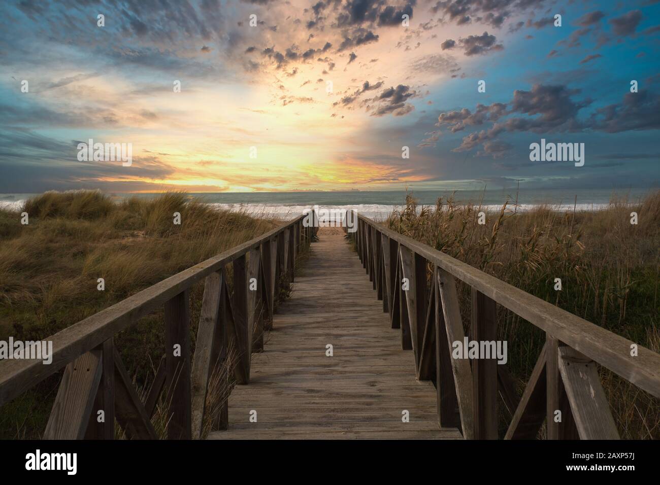 Sentiero in legno e tramonto sulla spiaggia di El Palmar, vicino al Caños de Meca, un luogo ideale per trascorrere una grande vacanza sulla costa della provincia di Cadi Foto Stock