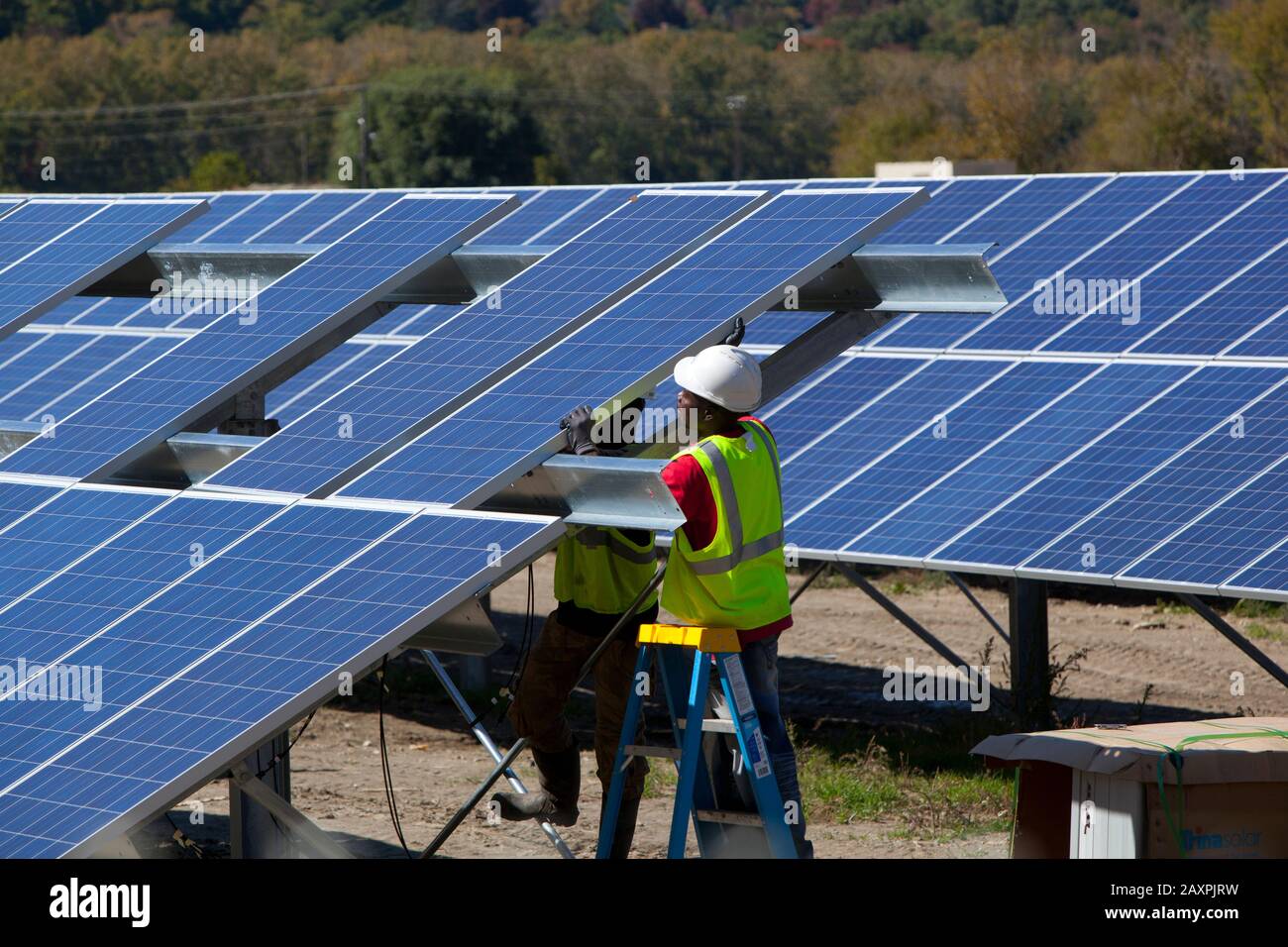Operai che installano una serie di pannelli solari in un campo aperto nel Vermont meridionale Foto Stock