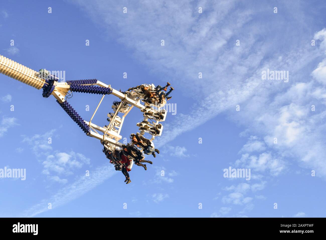 La gente sospesa in aria su un giro spaventoso nel parco divertimenti contro il cielo azzurro, Sanremo, Liguria, Italia Foto Stock