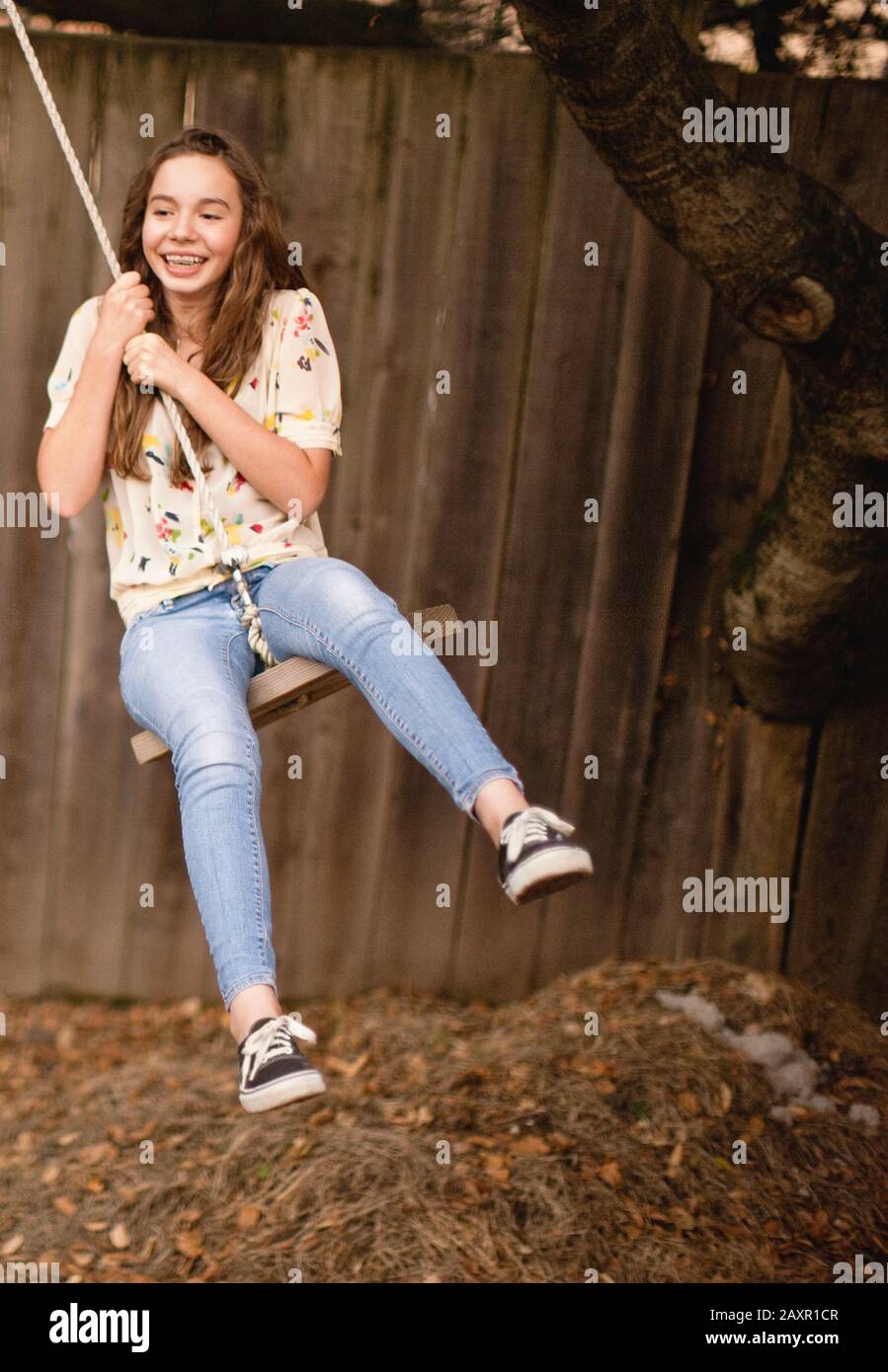 Ragazza adolescente su swing corda nel cortile. Foto Stock