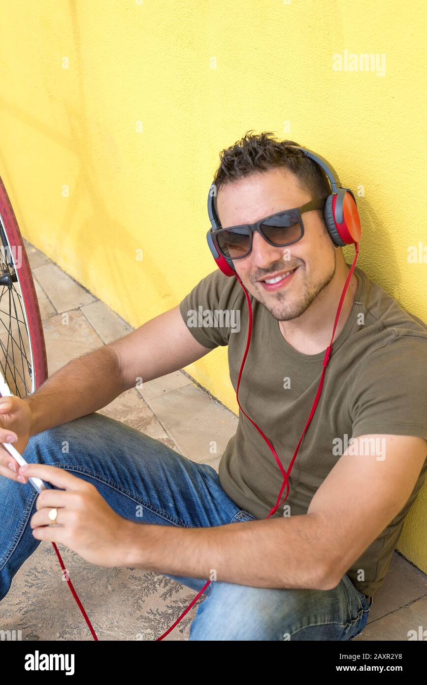 Uomo sorridente sorridente mentre utilizzando le sue cuffie Foto Stock