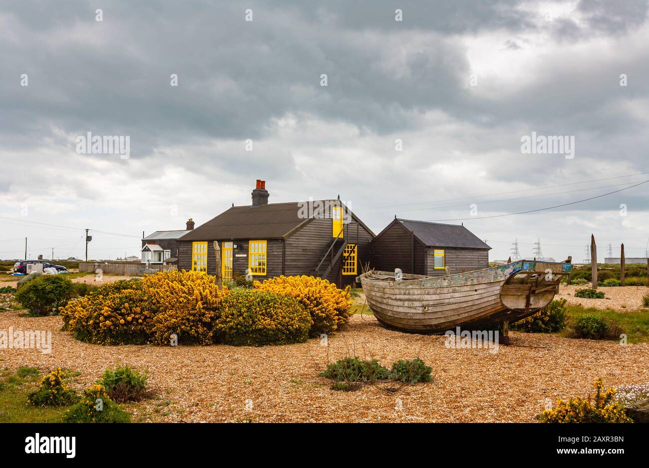 Vista laterale di Prospect Cottage, casa di Derek Jarman, regista, sulla spiaggia di ghiaia a Dungeness, quartiere Shepway, Kent con vecchia barca Foto Stock