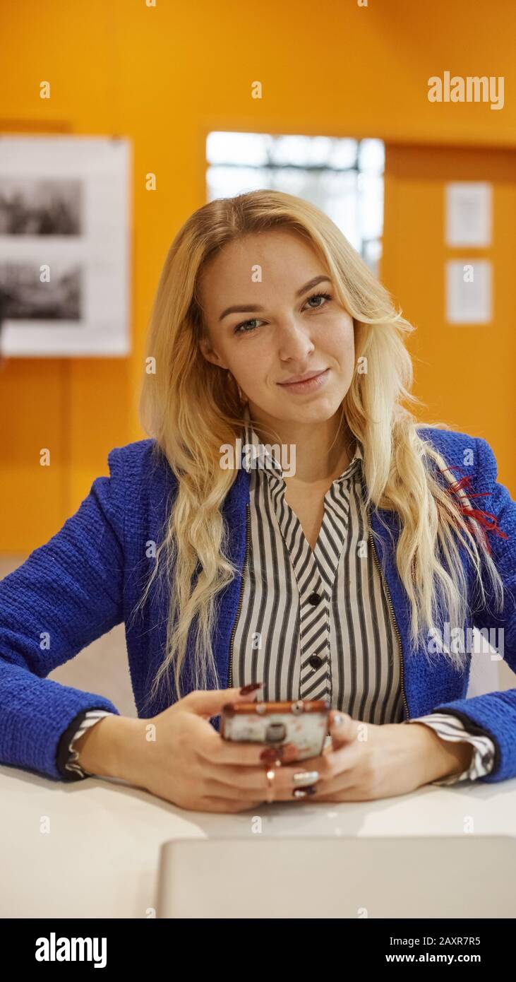 donna di affari sorridente in giacca blu in ufficio Foto Stock