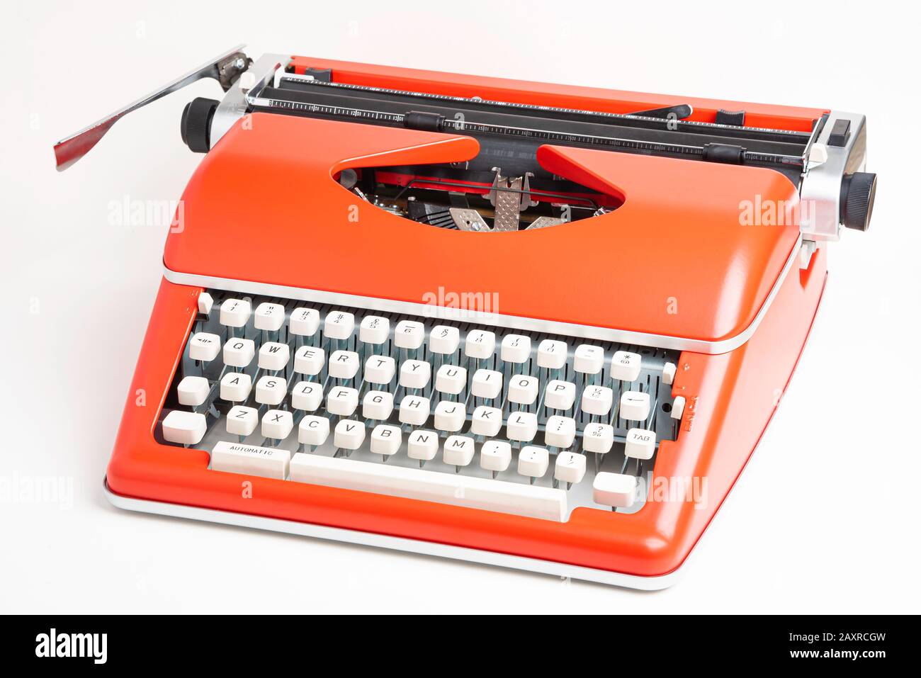 Un'immagine da studio di una macchina da scrivere manuale in stile retrò con tastiera in plastica color avorio e rivestimento in metallo rosso-arancione. Foto Stock