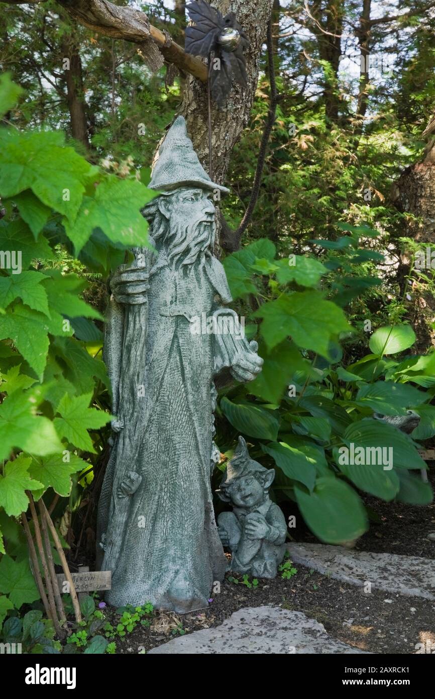 Statua di Merlin e leprechaun in cortile giardino di campagna in estate Foto Stock