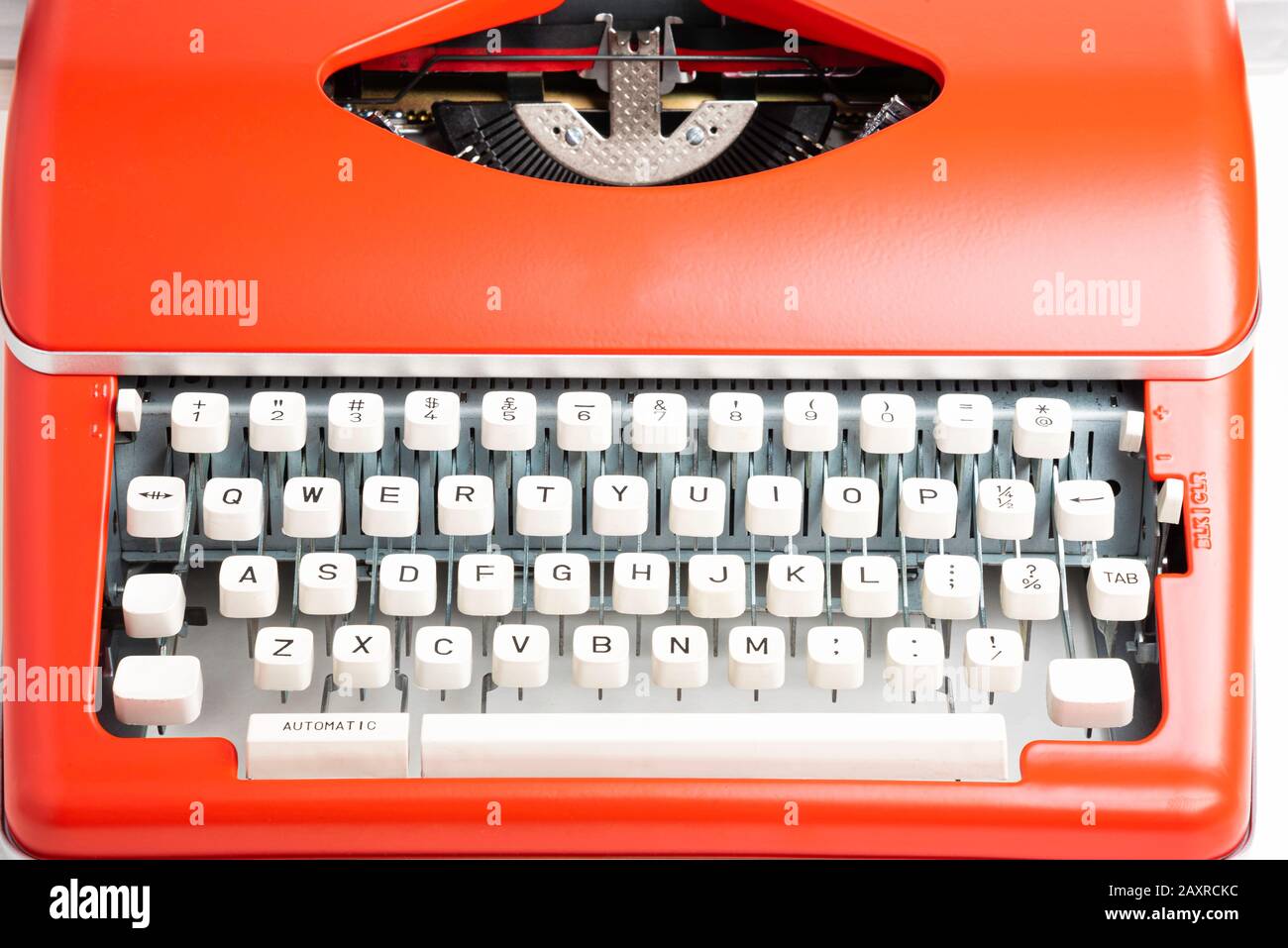 Un'immagine da studio di una macchina da scrivere manuale in stile retrò con tastiera in plastica color avorio e rivestimento in metallo rosso-arancione. Foto Stock