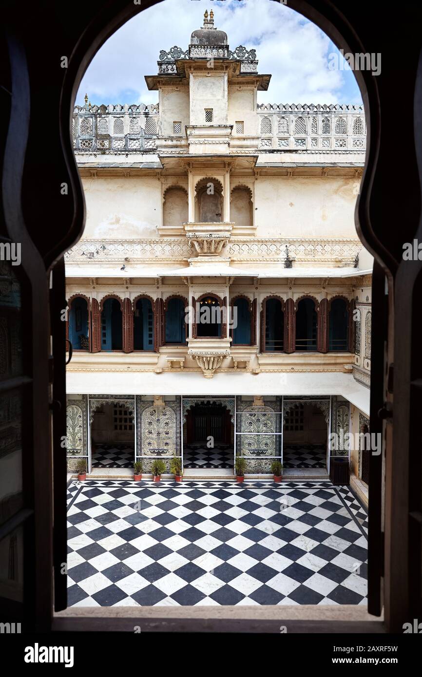 Museo del Palazzo della Città con pavimento a scacchi e bella architettura a Udaipur, Rajasthan, India. Vista dalla silhouette della finestra ad arco. Foto Stock