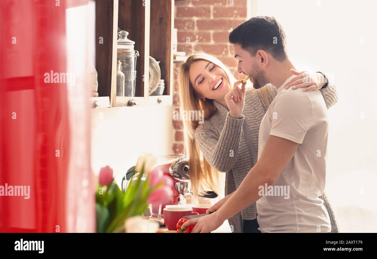 Donna che alimenta il suo ragazzo con un pezzo di paprika prima della colazione Foto Stock