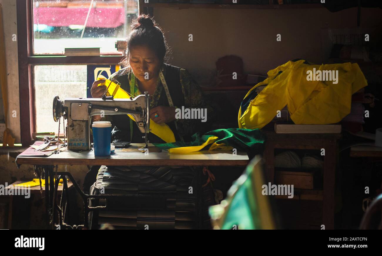 Una lavoratrice tibetana femminile che lavora con una macchina da cucire in un piccolo laboratorio a Mcleodganj, Himachal Pradesh. Foto Stock