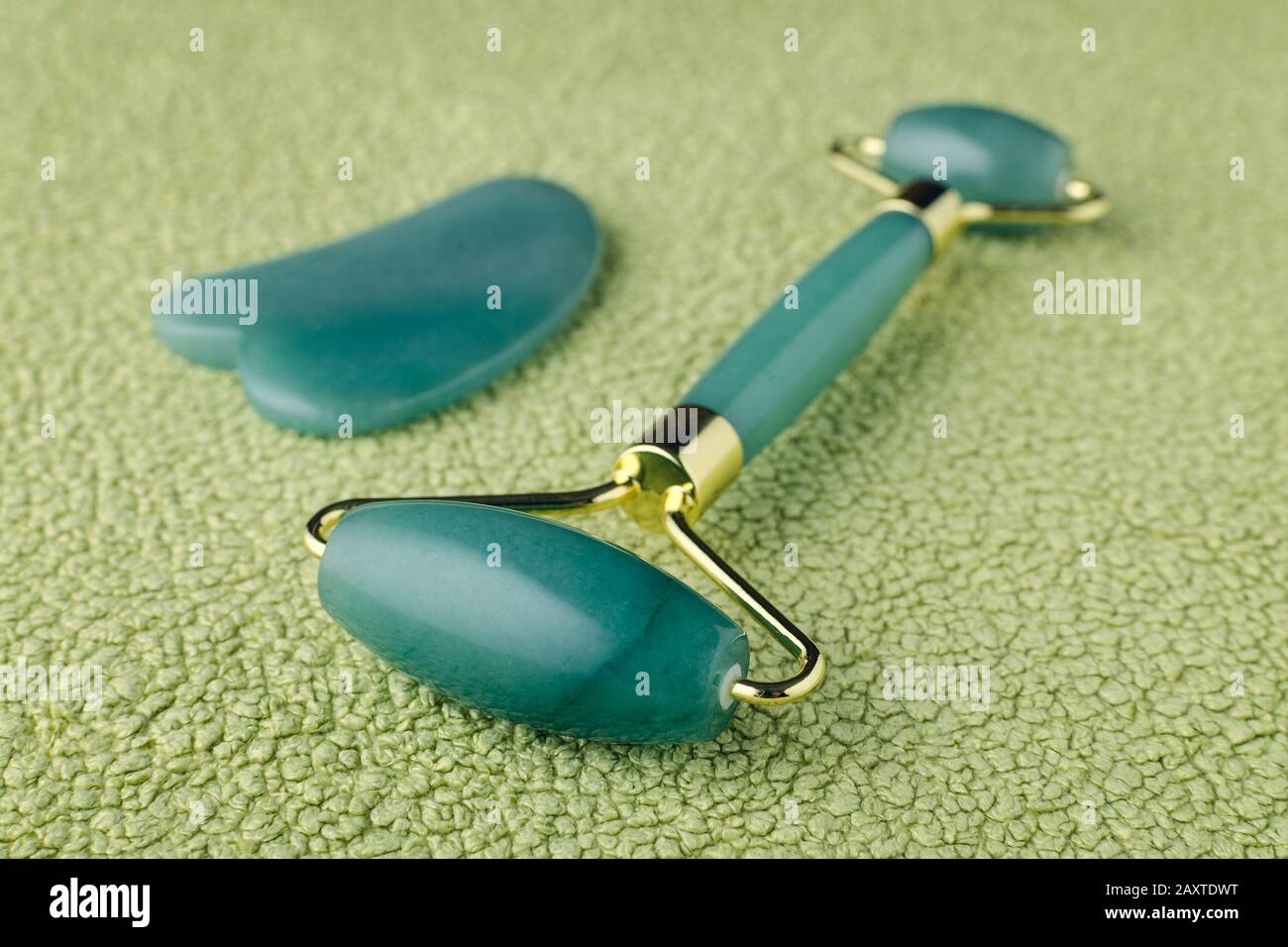 real jade rullo viso e massaggio pietra gua sha su sfondo verde, closeup Foto Stock