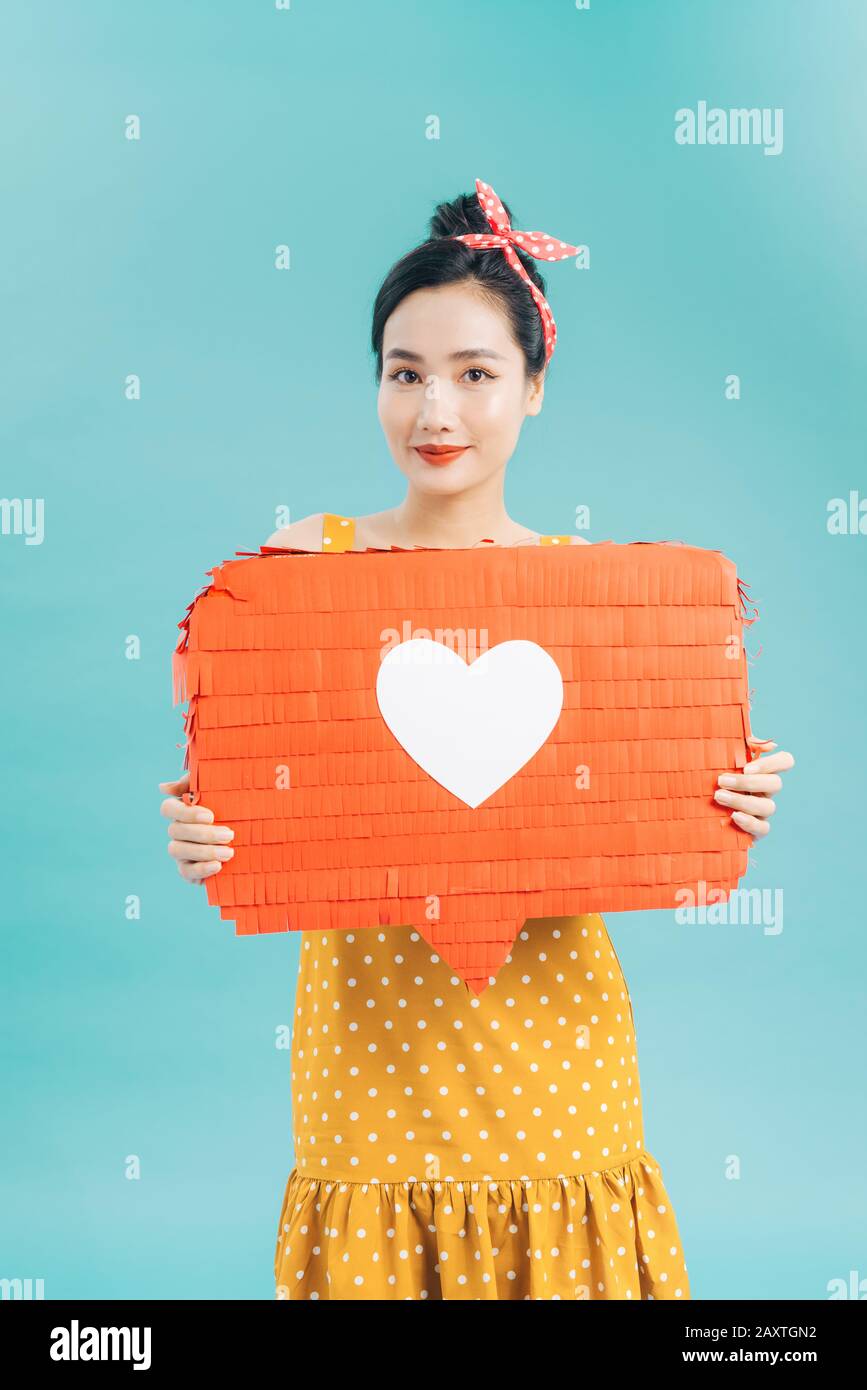 Giovane donna in abito casual azienda banner con come icona e guardando la telecamera mentre che simboleggiano i social media contro lo sfondo blu Foto Stock