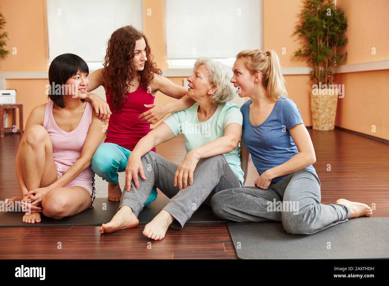 Le donne parlano come amici di un gruppo in una lezione di yoga Foto Stock