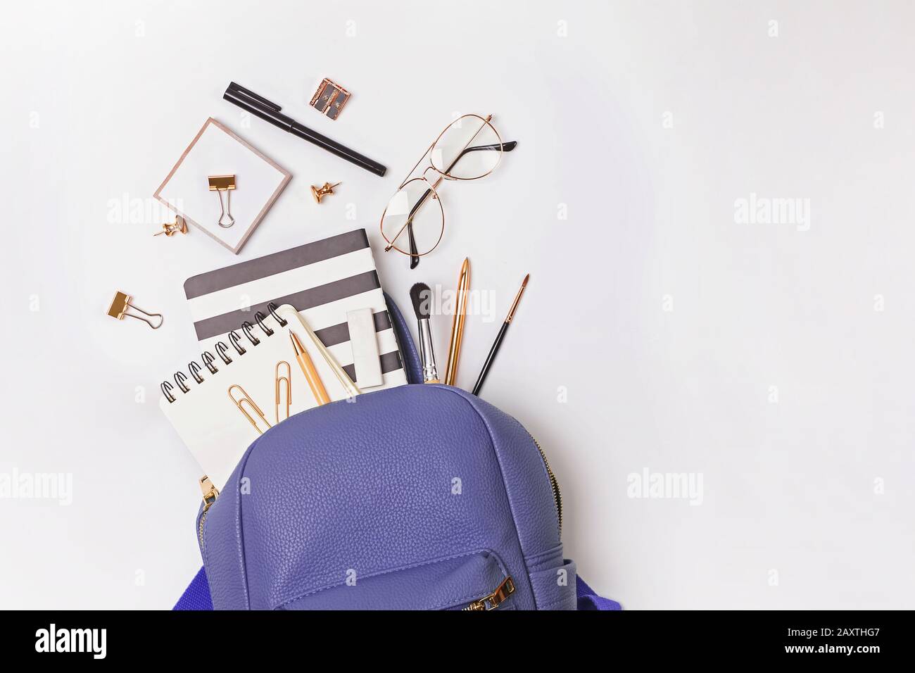 Zaino con diversi articoli di cancelleria e di studio sullo sfondo bianco Foto Stock