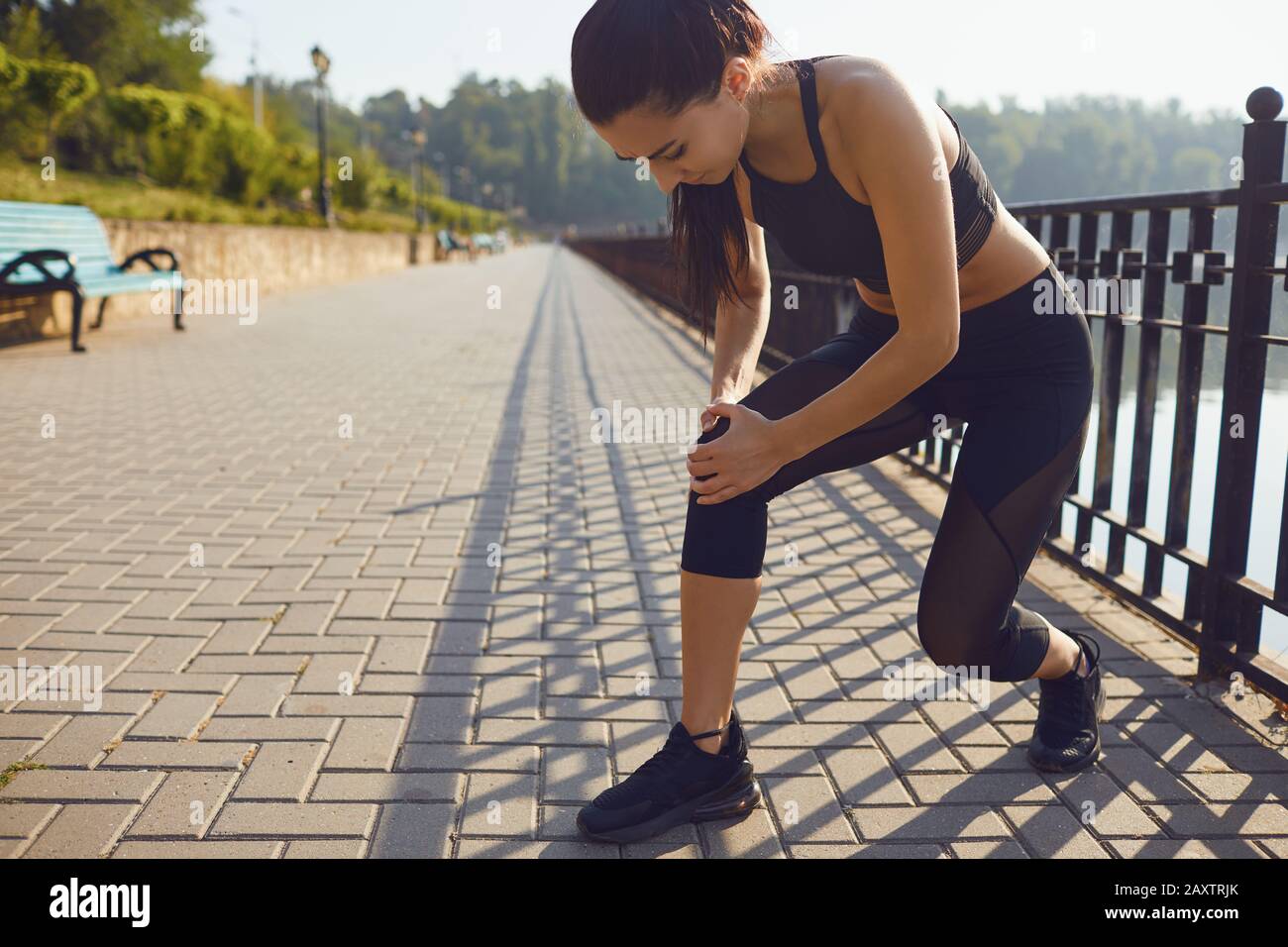 Infortunio al ginocchio in atleta ragazza nel parco. Foto Stock