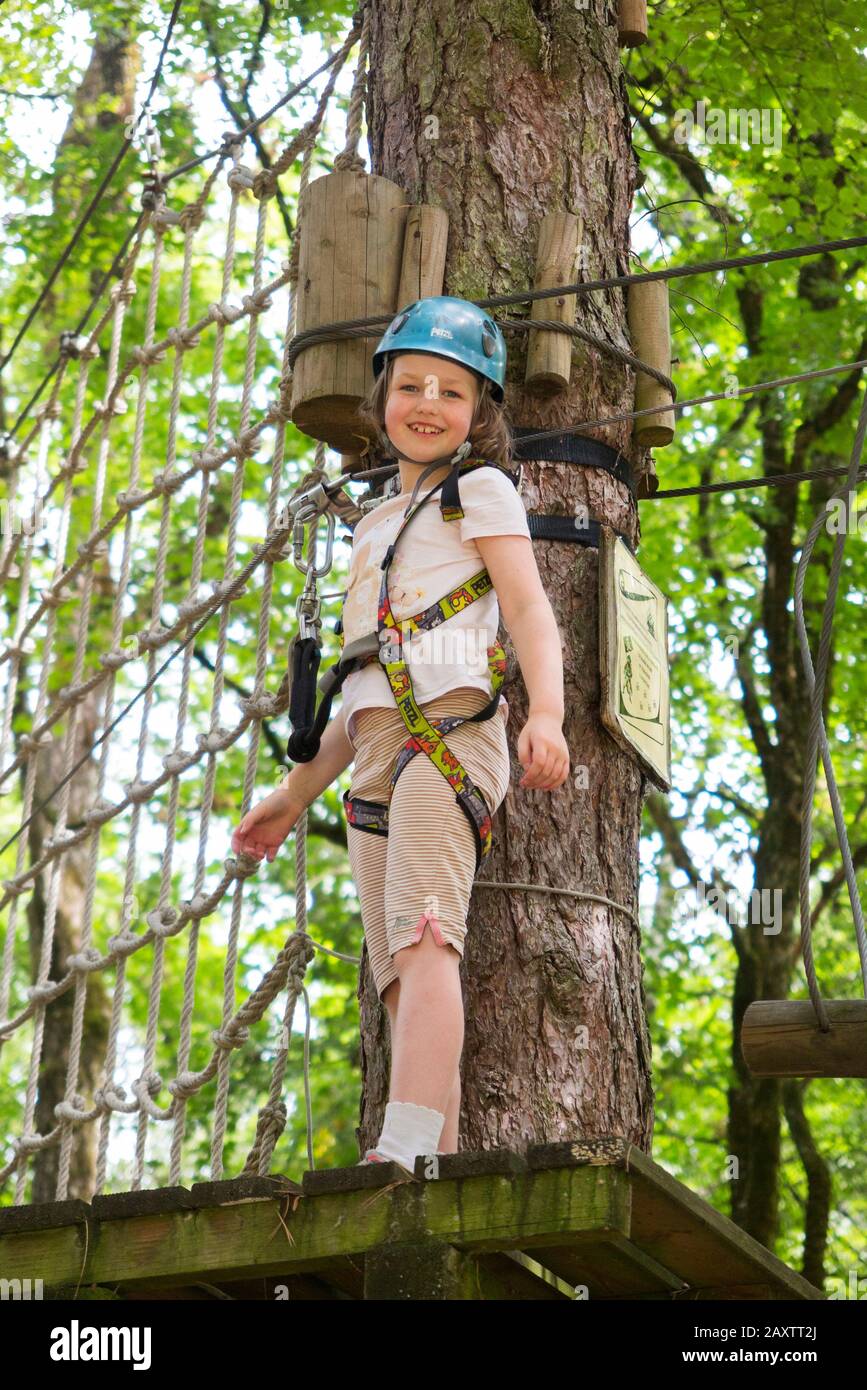 Ragazza giovane ragazza bambino bambino su un bambino ostacolo corso attività Trail in alto nel bosco foresta albero, in un parco avventura in Francia durante l'estate. (112) Foto Stock