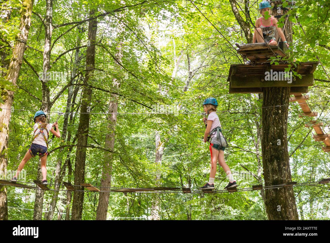 Tre ragazze ragazza bambino bambino bambino su un bambino ostacolo attività corso Trail alto in foresta albero, in un parco avventura in Francia durante l'estate. (112) Foto Stock