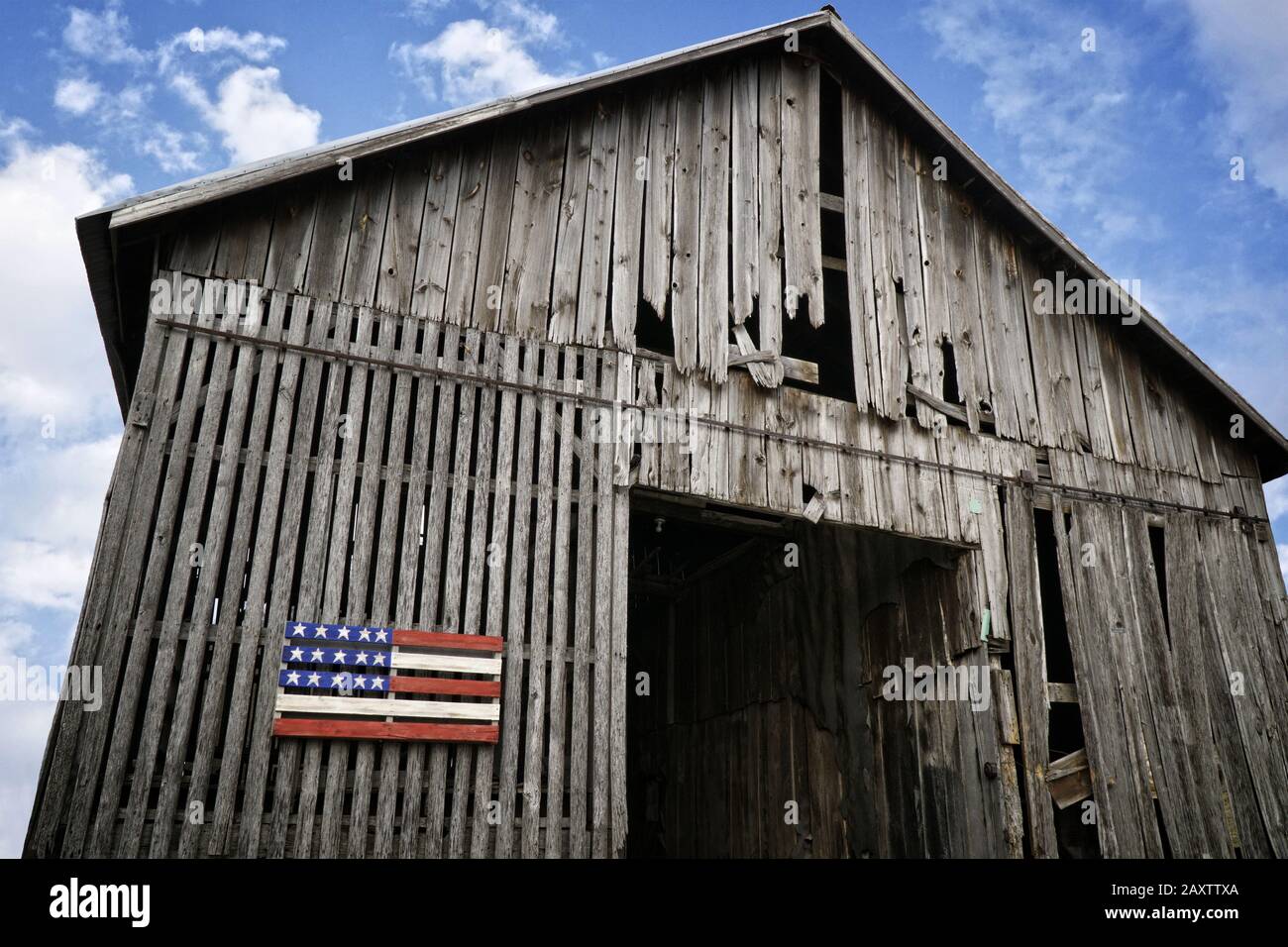 Tiro ad angolo basso di un vecchio fienile di legno con un bandiera americana in legno dipinto Foto Stock