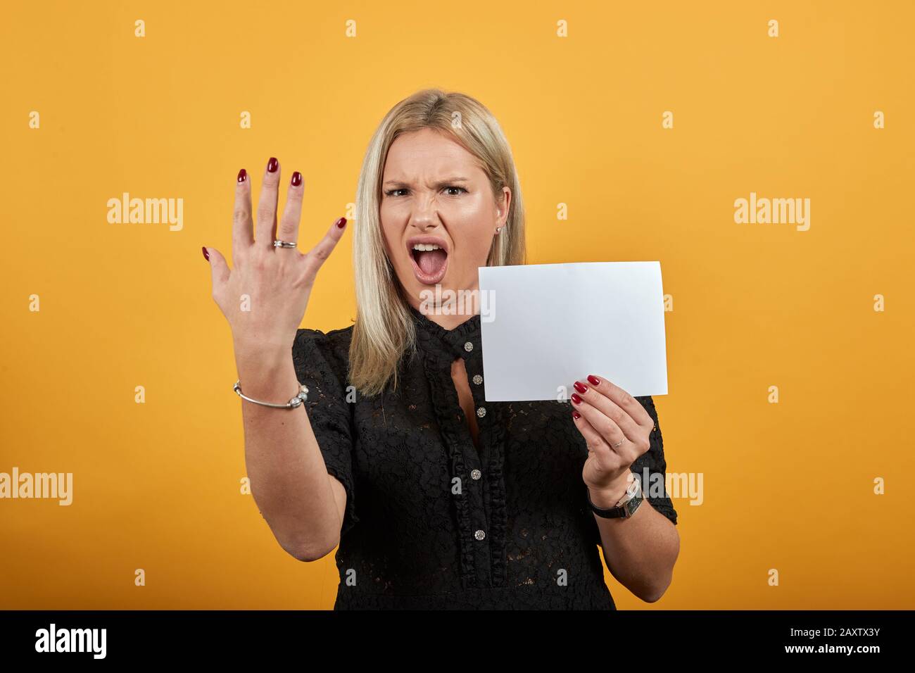 la donna irritata tiene un foglio vuoto di carta in mano e dita di demosnstrut Foto Stock