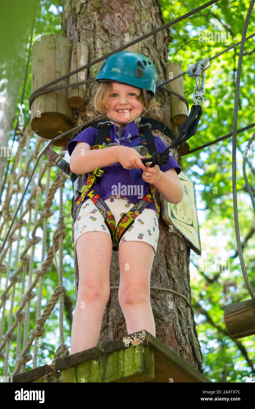 Ragazza giovane ragazza bambino bambino su un bambino ostacolo corso attività Trail in alto nel bosco foresta albero, in un parco avventura in Francia durante l'estate. (112) Foto Stock