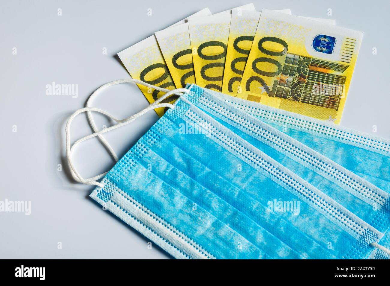 Maschere mediche e banconote da 200 euro come simbolo di un aumento dei prezzi per la protezione del tratto respiratorio dai virus. Foto Stock