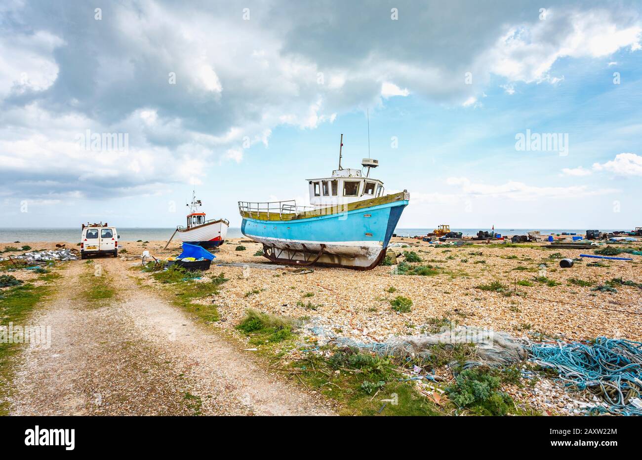 Vecchie barche da pesca hanno trasportato su e hanno abbaiato sulla spiaggia di ghiaia a Dungeness, distretto di Shepway, Kent in una giornata di primavera soleggiata Foto Stock