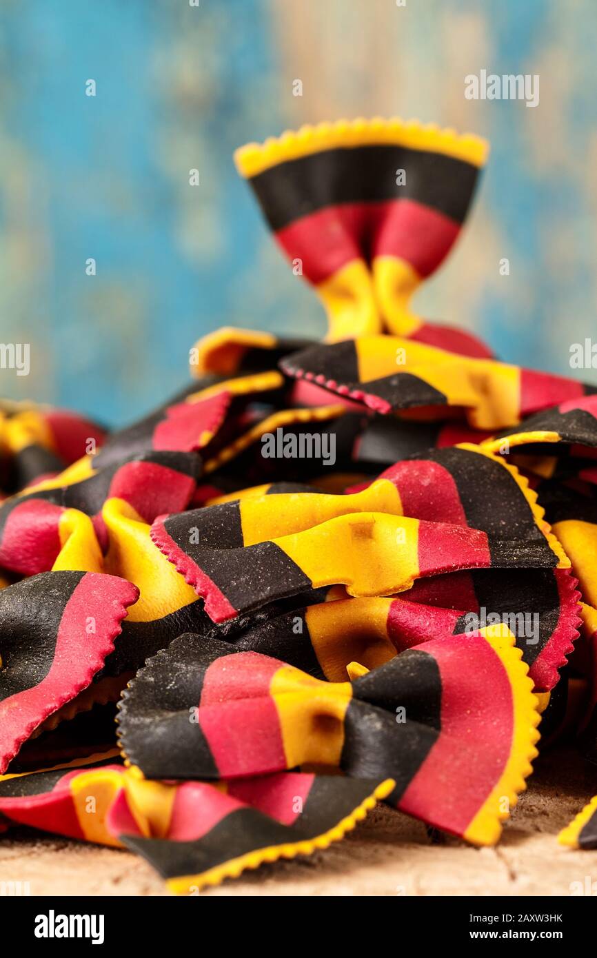 Pasta farfalle italiana cruda multicolore a spicchio su tavola rustica Foto Stock