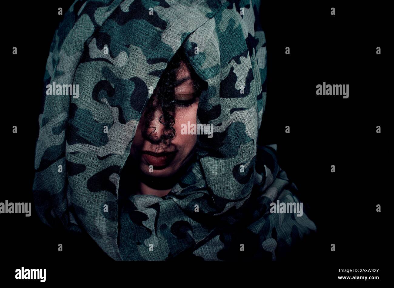 Ritratto di una donna nera che indossa un copricapo camouflage e che guarda verso il basso. Guerra, concetto di lotta. Foto Stock