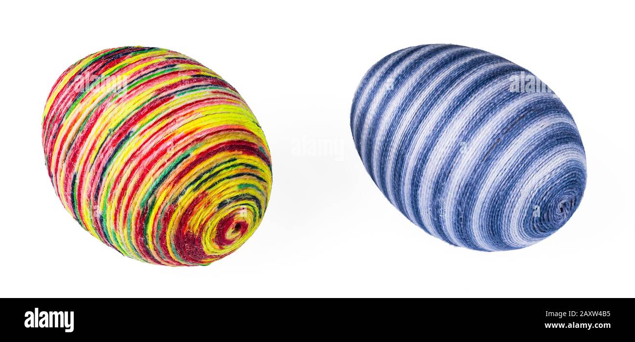 Due colorate uova di Pasqua striate decorate a mano da un sottile filato di cotone incollato o spago verniciato. Decorazione originale ornata vacanza da gusci di pollo. Foto Stock