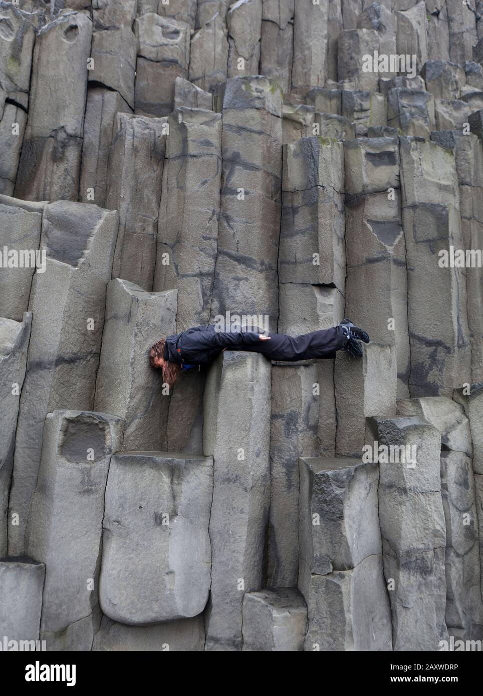 Teenager su colonne basaltiche a Reynisfjara, Costa Sud, Islanda Foto Stock
