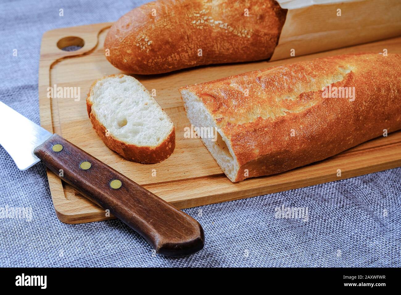 Baguette calda fresca con crosta croccante. Affettato per colazione. Per il sandwich mattutino. Foto Stock