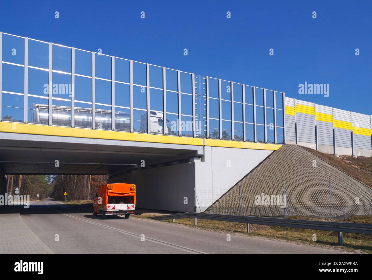 Autostrada circondata da barriere fonoassorbenti. Sotto l'autostrada, un viadotto per la strada locale. Foto Stock