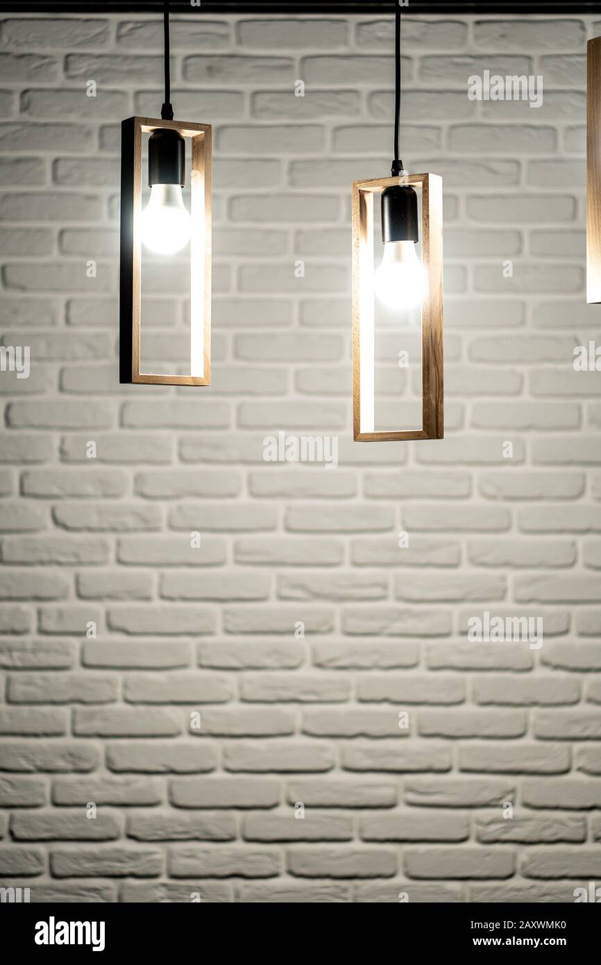 Tre lampade su uno sfondo di un muro di mattoni bianchi. Tre lampadine su uno sfondo bianco di mattoni. Sfondo in mattoni bianchi con tre vortici che appendono Foto Stock