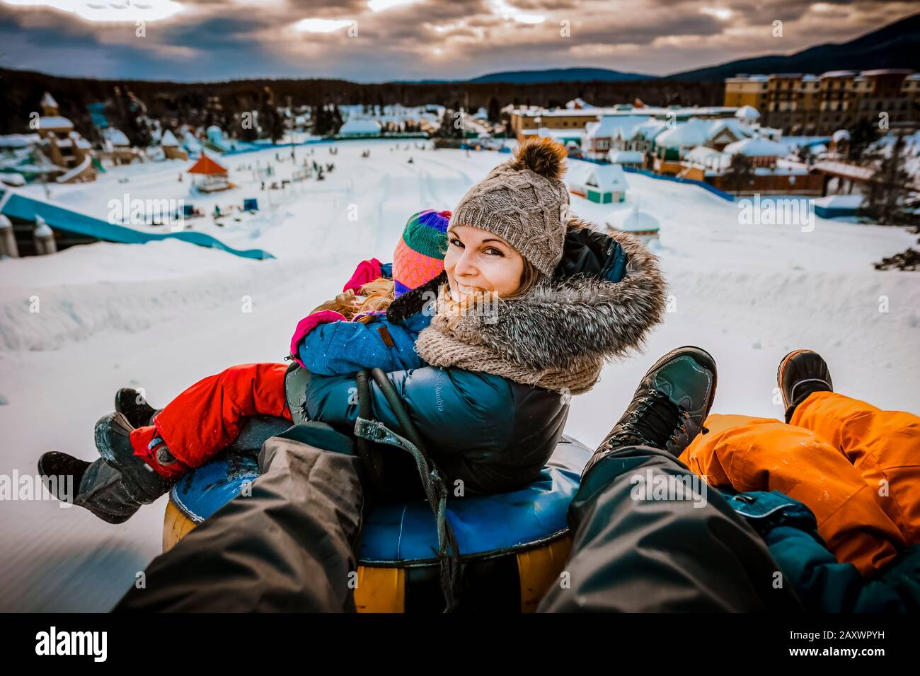 Madre scivola con la sua famiglia sui tubi durante una giornata invernale Foto Stock