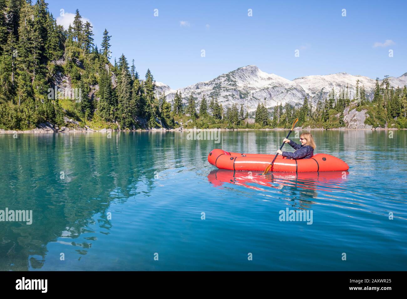 Donna in pensione pagaia barca rossa sul lago remoto durante un viaggio. Foto Stock