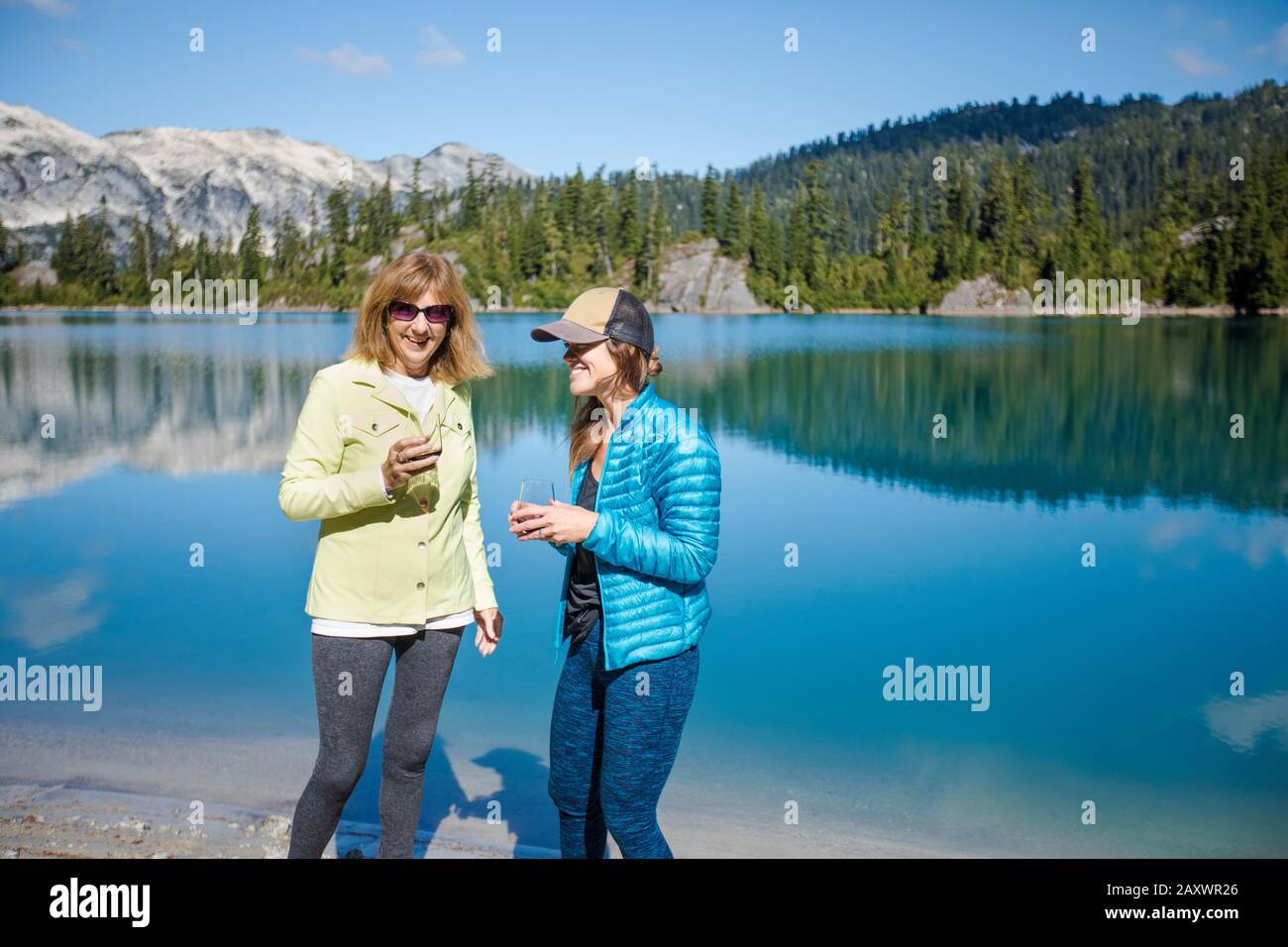 Madre e figlia godono di un bicchiere di vino presso un lago di montagna. Foto Stock