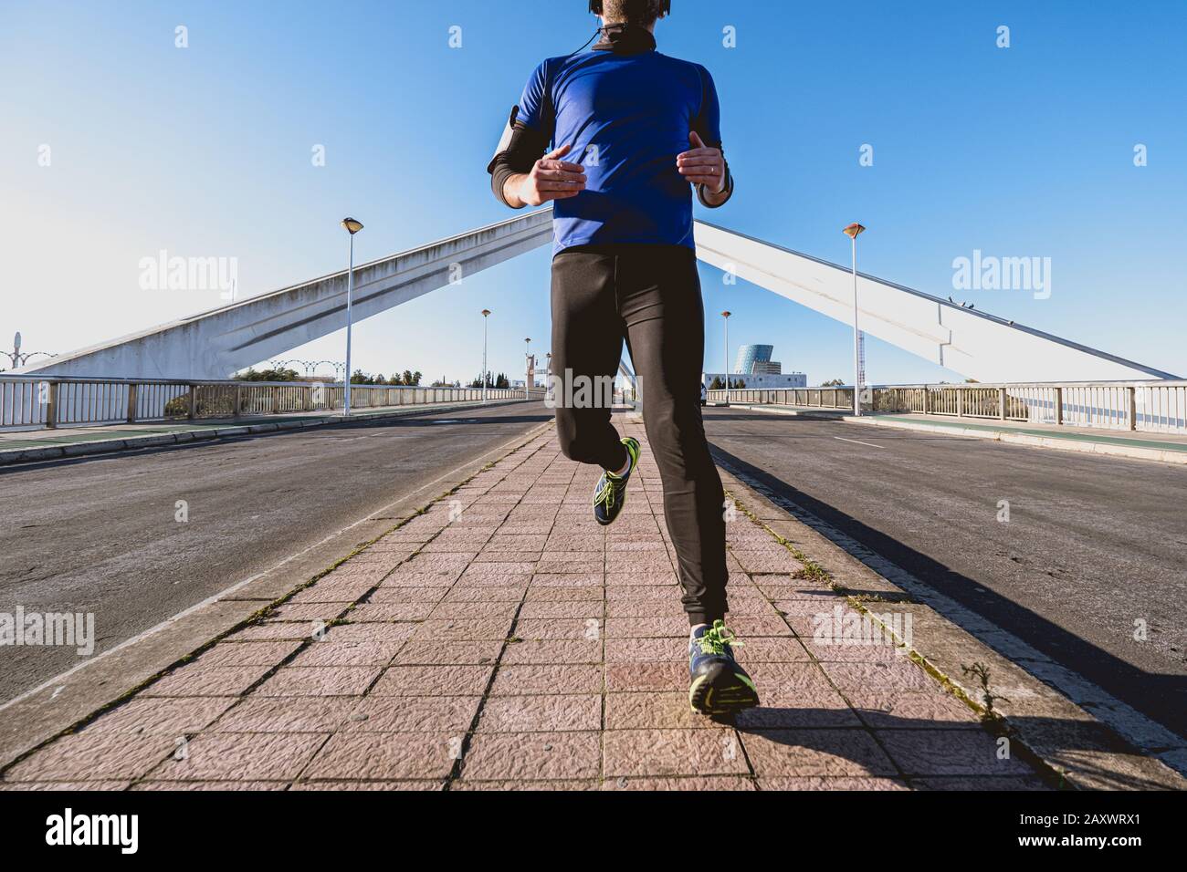 giovane uomo che corre lungo la strada di fronte a un ponte Foto Stock