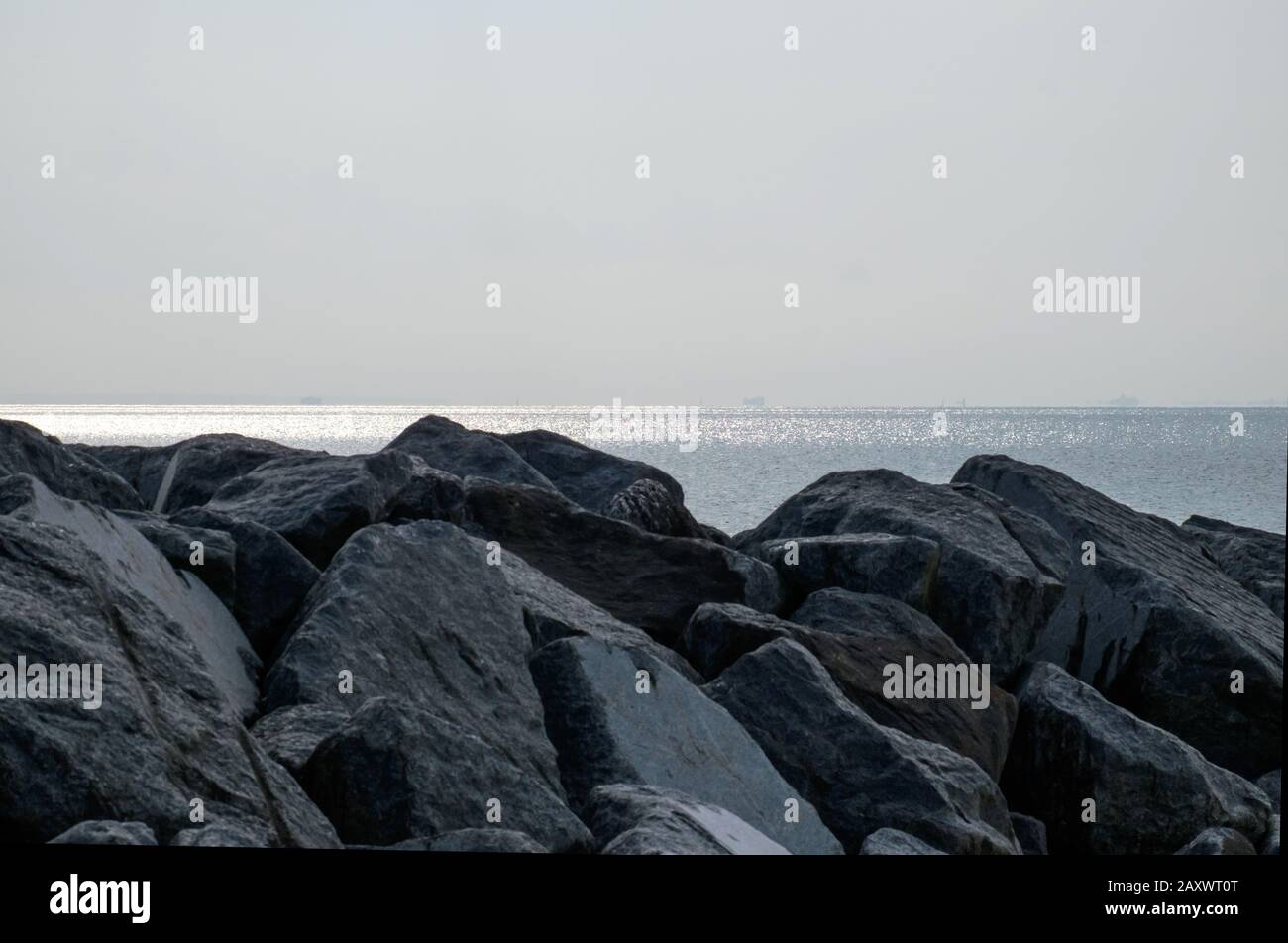 Rocce in primo piano con oceano e orizzonte sullo sfondo, prima sera estate. Bella Spiaggia, West Sands Selsey, West Sussex, Inghilterra. Foto Stock
