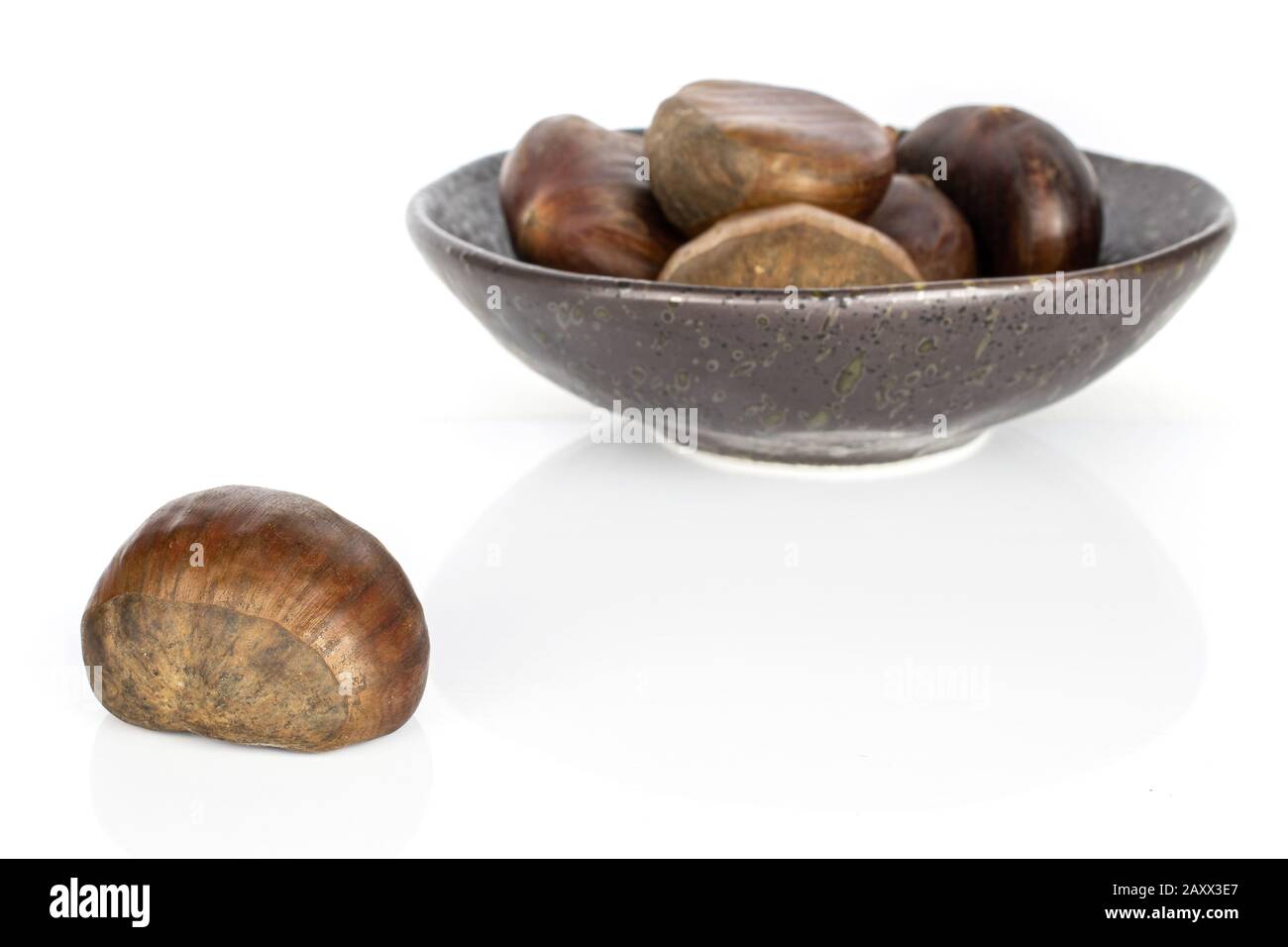 Gruppo di cinque castagne marroni commestibili intere in ciotola smaltata isolata su fondo bianco Foto Stock