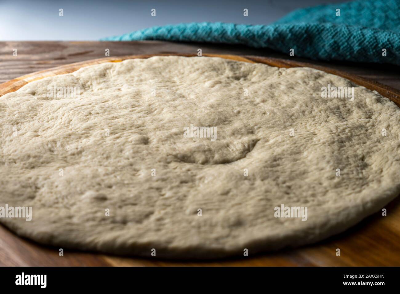 Pasta per pizza appoggiata su buccia di legno. Foto Stock