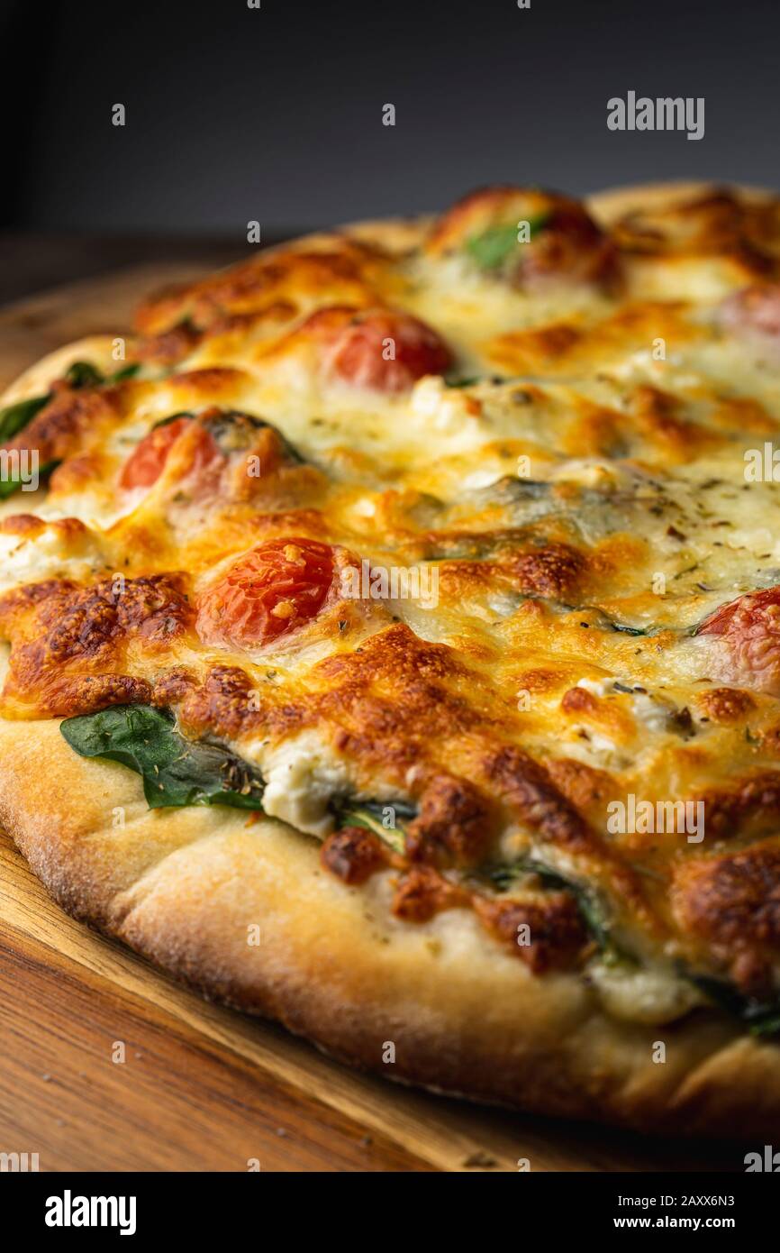 Pizza vegetariana con spinaci, pomodori, feta, carciofi e mozzarella. Foto Stock