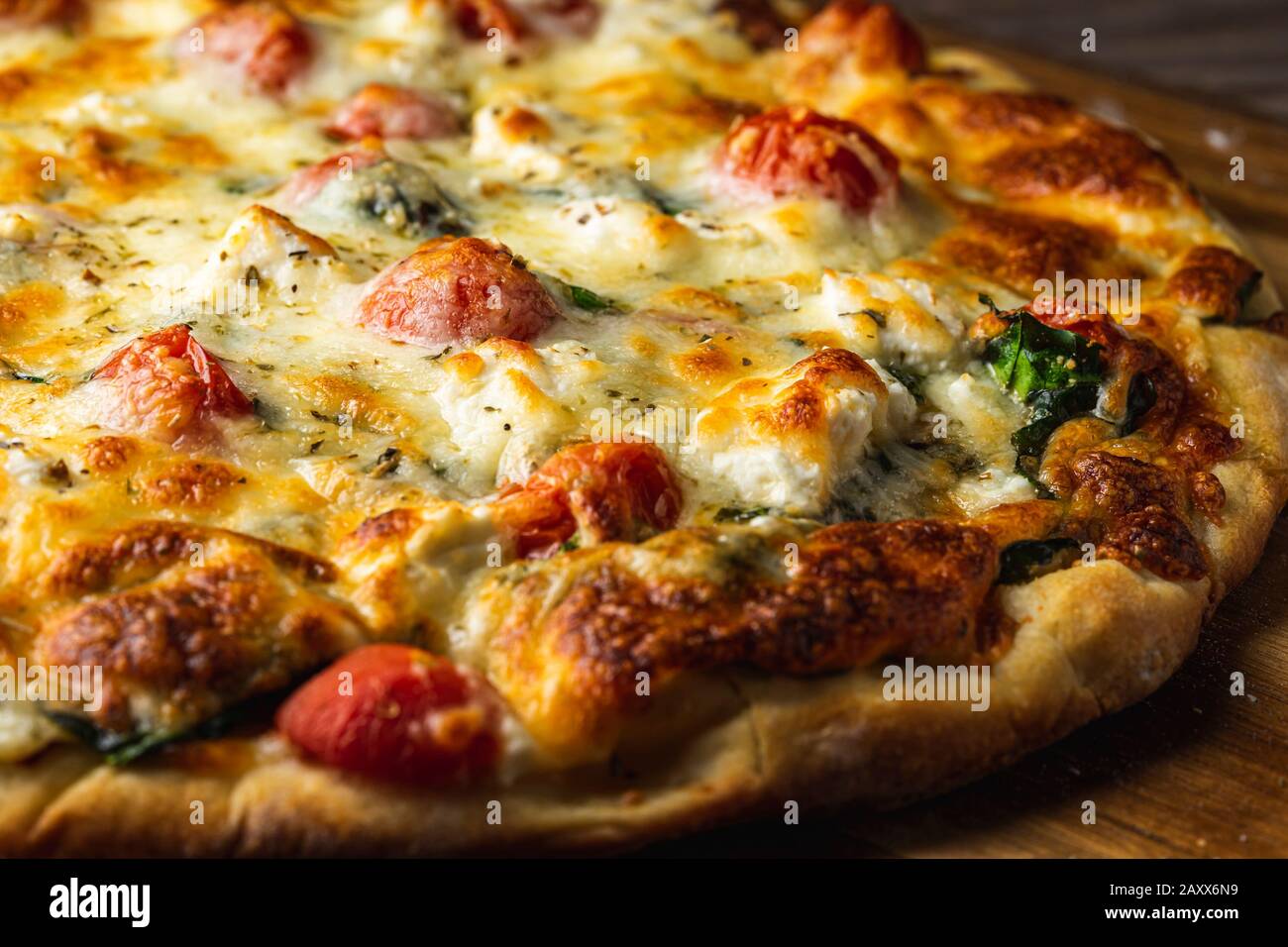 Pizza vegetariana con spinaci, pomodori, feta, carciofi e mozzarella. Foto Stock