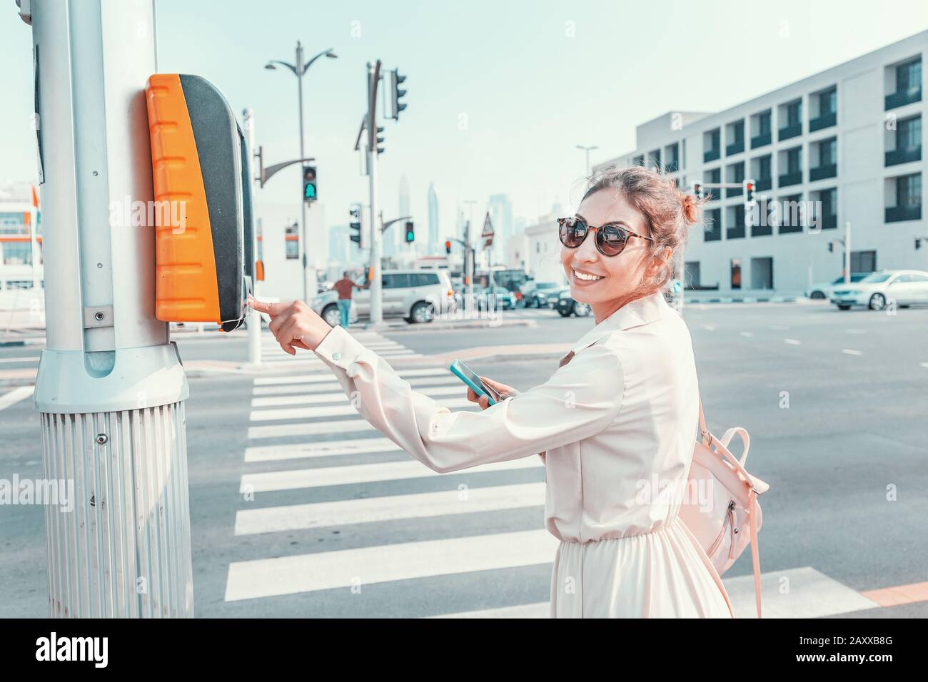 Ragazza pedonale preme il pulsante per attraversare la strada in modo sicuro. Design urbano di una città sicura Foto Stock