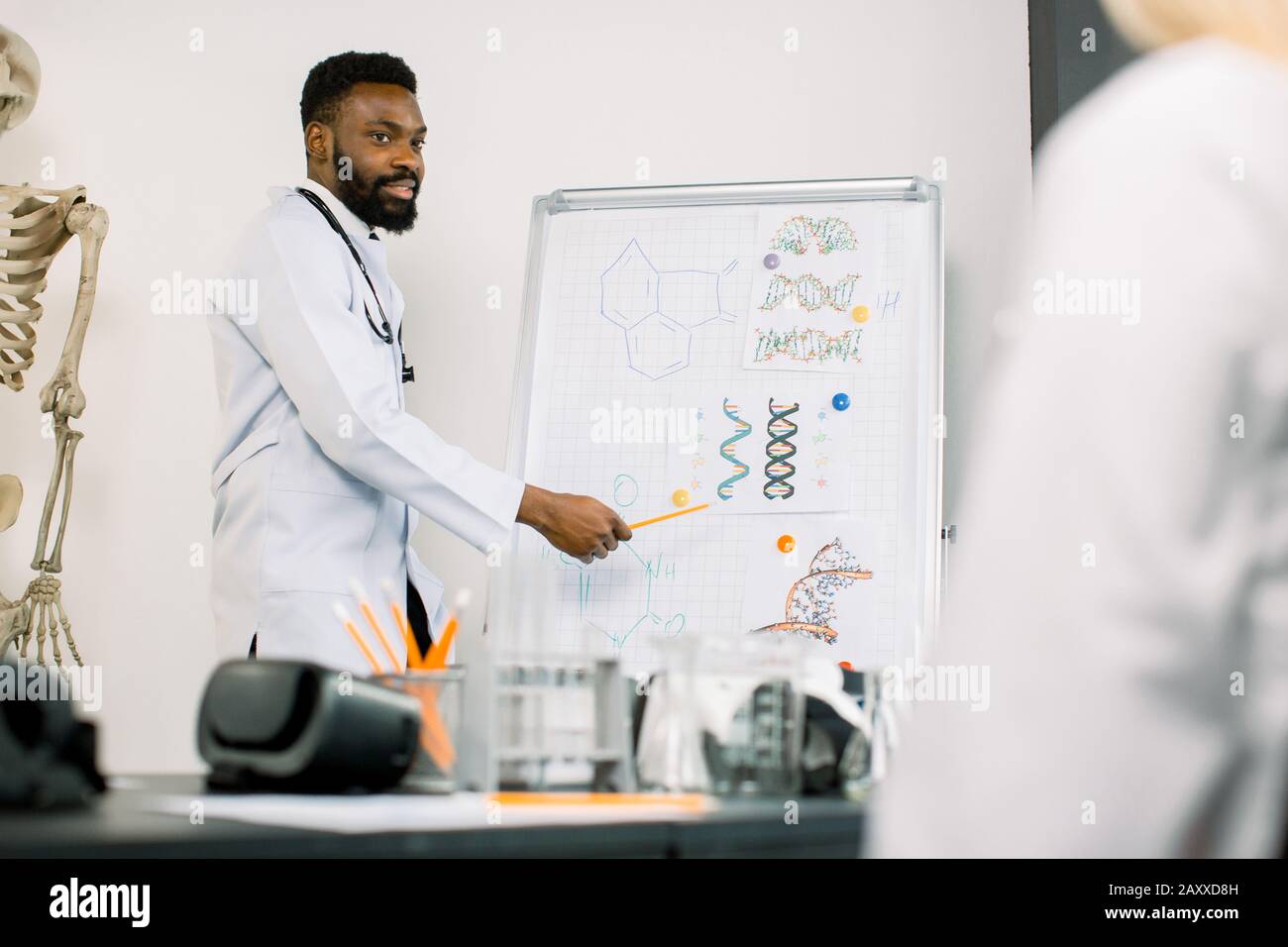 Ritratto di giovane medico africano o biochimico che mostra a bordo alcune formule biochimiche per i suoi colleghi nella sala conferenze. Medicina Foto Stock