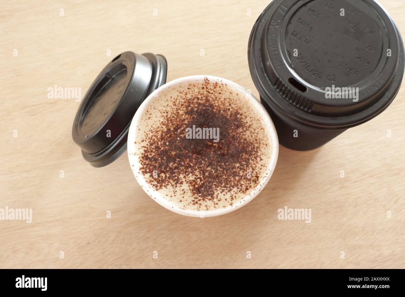 Due tazze di caffè da asporto ghiacciato appena fatto in una tazza monouso, una con il coperchio rimosso per rivelare la bevanda, a tenuta, vista dall'alto Foto Stock