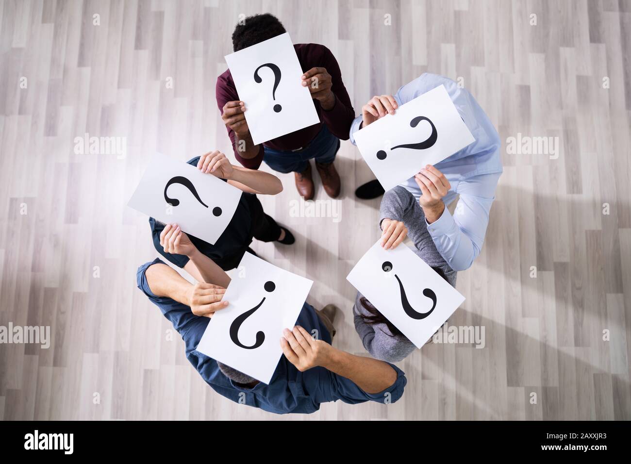 Gruppo di Business non identificabili persone che si nascondono sotto un punto interrogativo Foto Stock