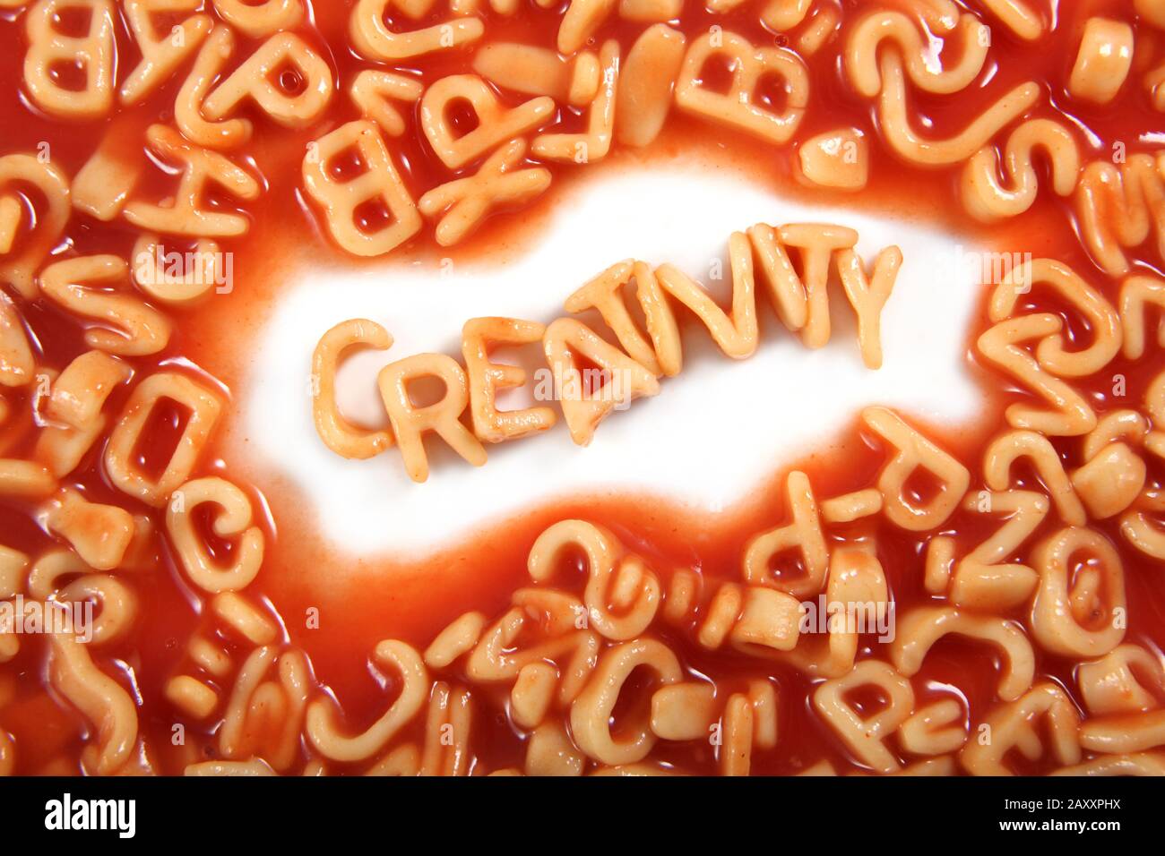 Creatività scritta in spaghetti lettere pasta circondato da lettere guazzate. Foto Stock