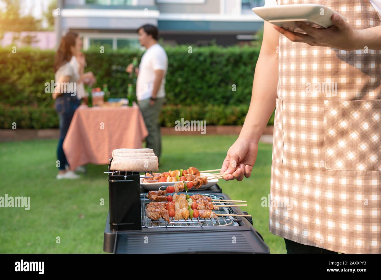 Cucina asiatica griglia barbecue e salsiccia per un gruppo di amici a mangiare in giardino a casa. Gruppo di amici con giardino all'aperto barbecue la Foto Stock