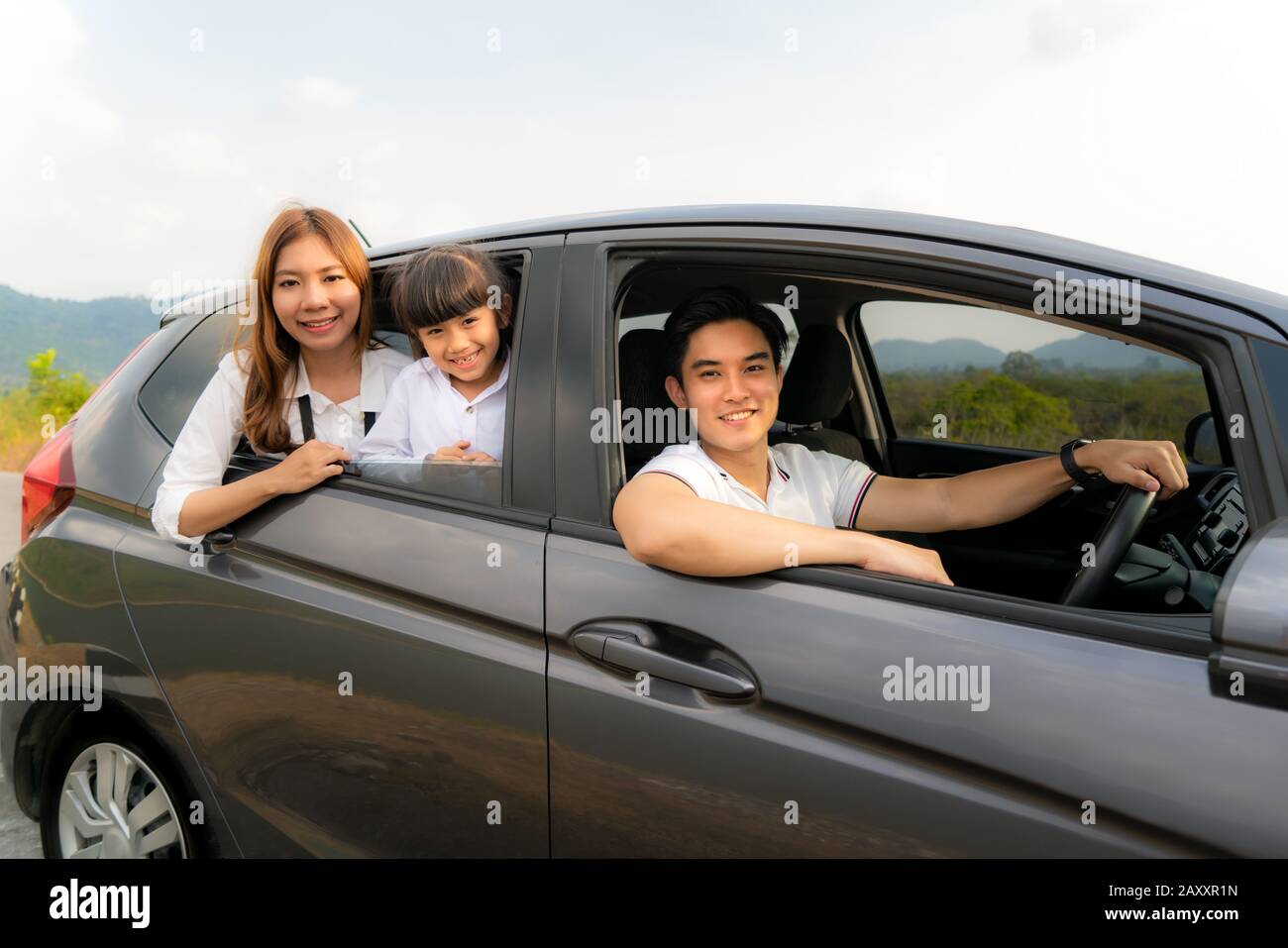 Felice famiglia asiatica con padre, madre e figlia in auto compatta sono sorridenti e guidare per viaggiare in vacanza. Assicurazione auto o noleggio e famiglia Foto Stock