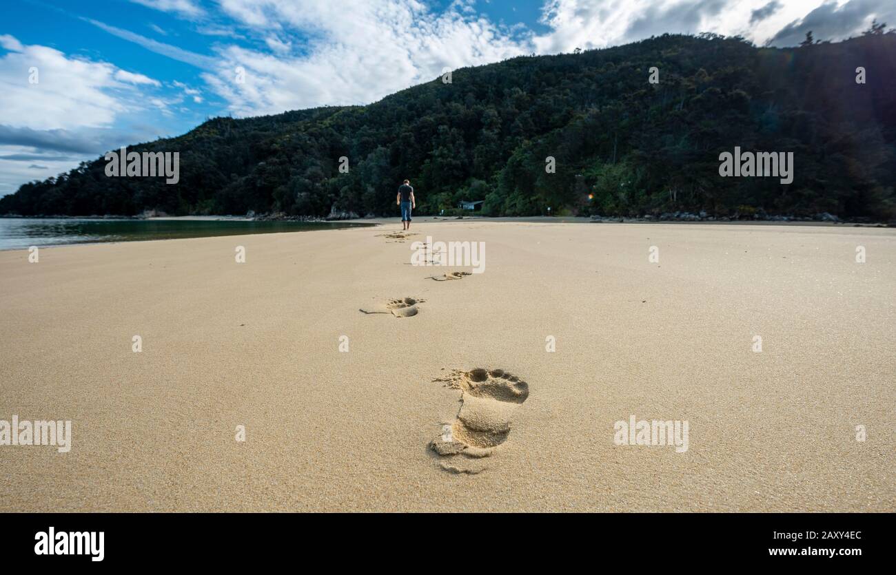 Impronte nella sabbia, giovane uomo sulla spiaggia di Stillwell Bay, Abel Tasman National Park, Tasman, South Island, Nuova Zelanda Foto Stock