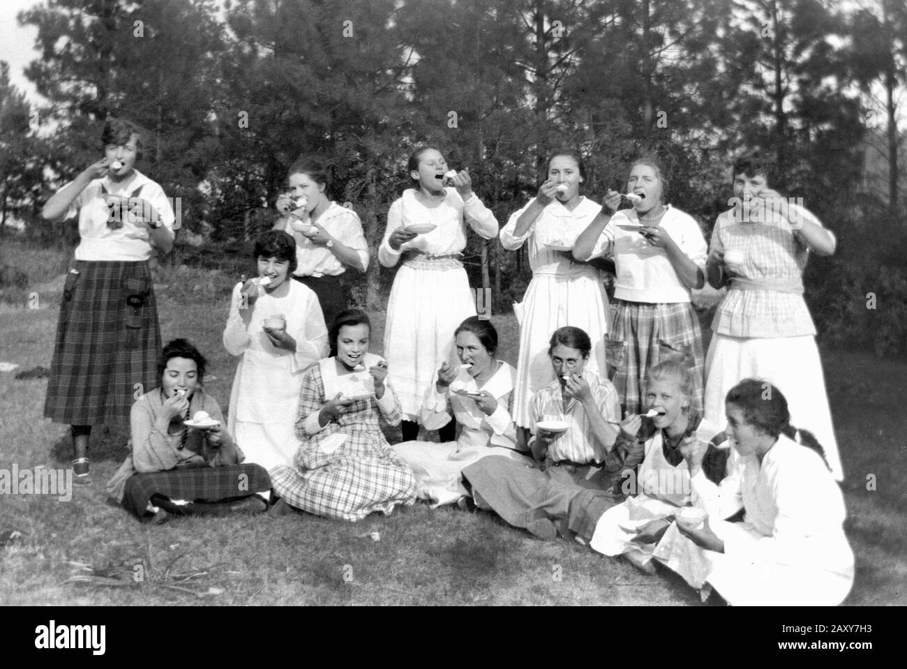 Un gruppo di giovani donne felici mangiano ciascuna un gelato all'unisono per una fotografia, ca. 1935. Foto Stock